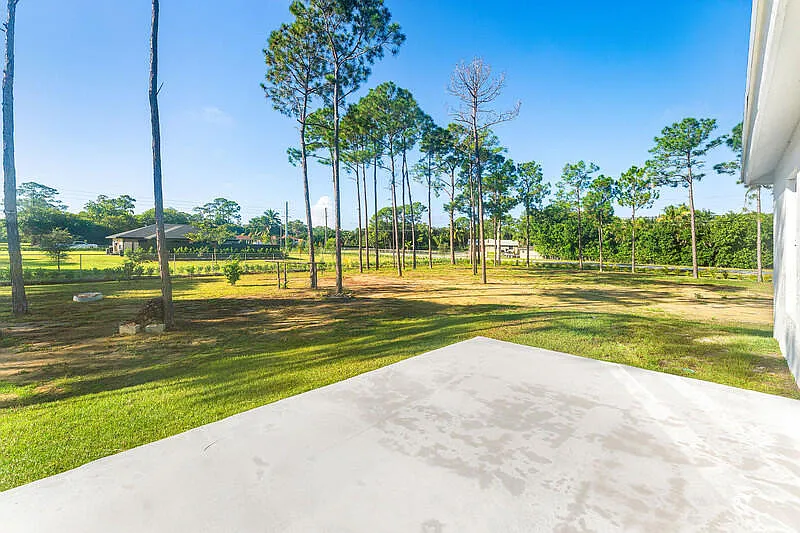 Rear patio and 1.36-acre lot with mature trees