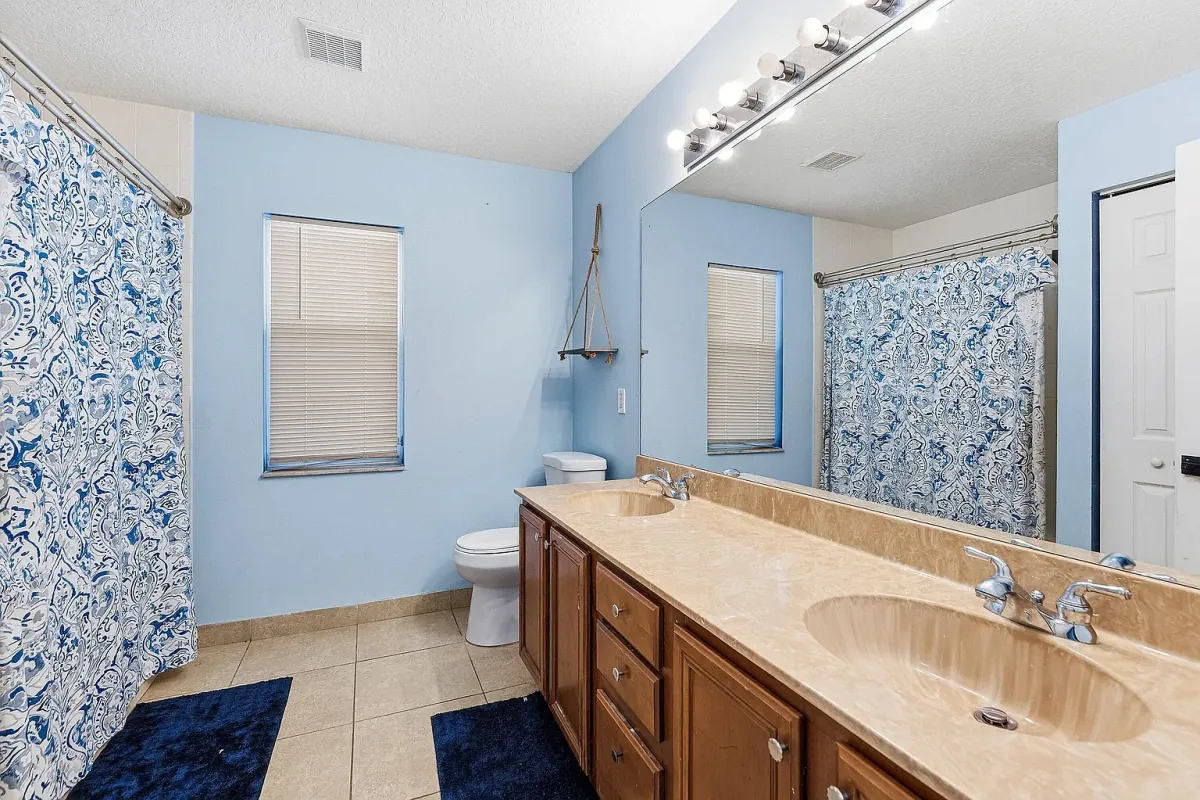 Full bathroom with patterned wallpaper and a double vanity