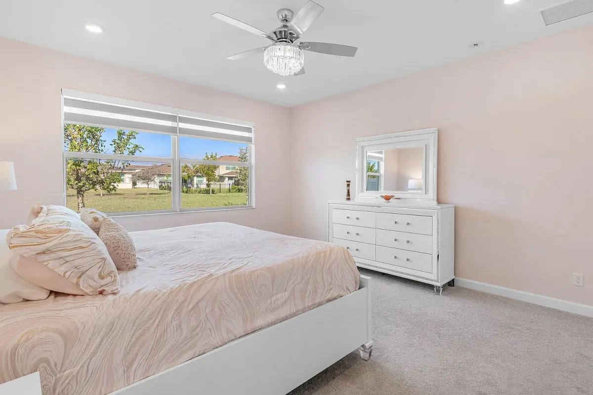 Bedroom with ceiling fan and window overlooking the rear yard
