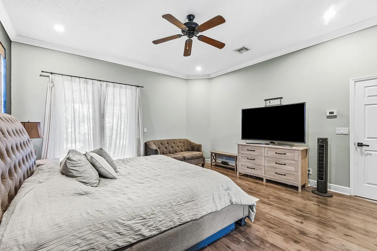Bedroom with ceiling fan, window seating and a wall-mounted TV