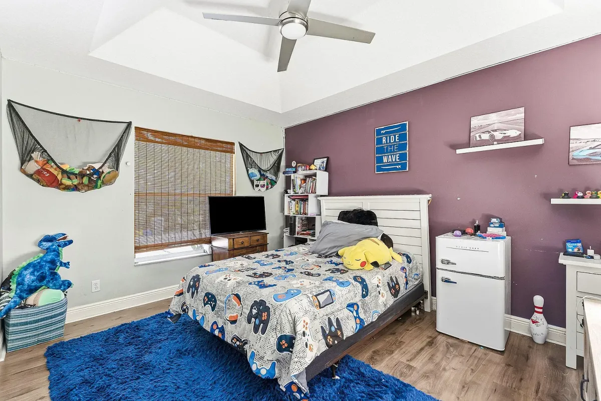 Bedroom with accent wall, ceiling fan and built-in storage