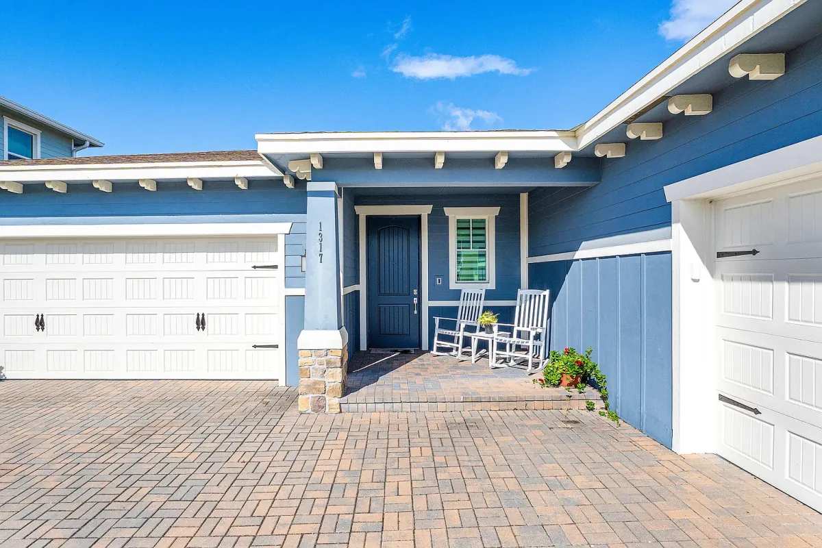 Paver courtyard entry between the garage bays, with covered front porch and rocking chairs