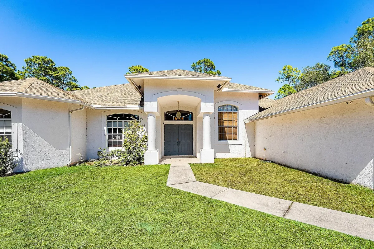 Front exterior of 17225 80th Street N, The Acreage, FL — stucco single-story home with arched entry and open lawn