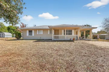 Front of the Okeechobee home, with a covered porch, standing-seam metal roof and attached carport