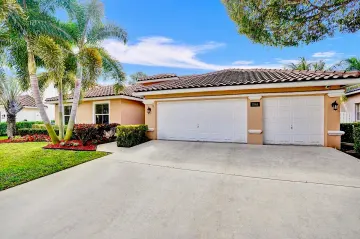 The home’s three-car garage and wide concrete driveway on a clear day