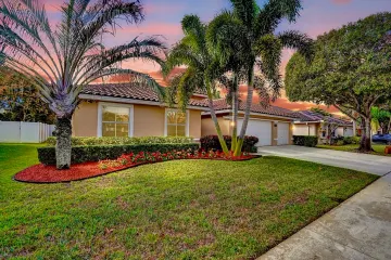 Landscaped front lawn and palm trees beside the home at sunset