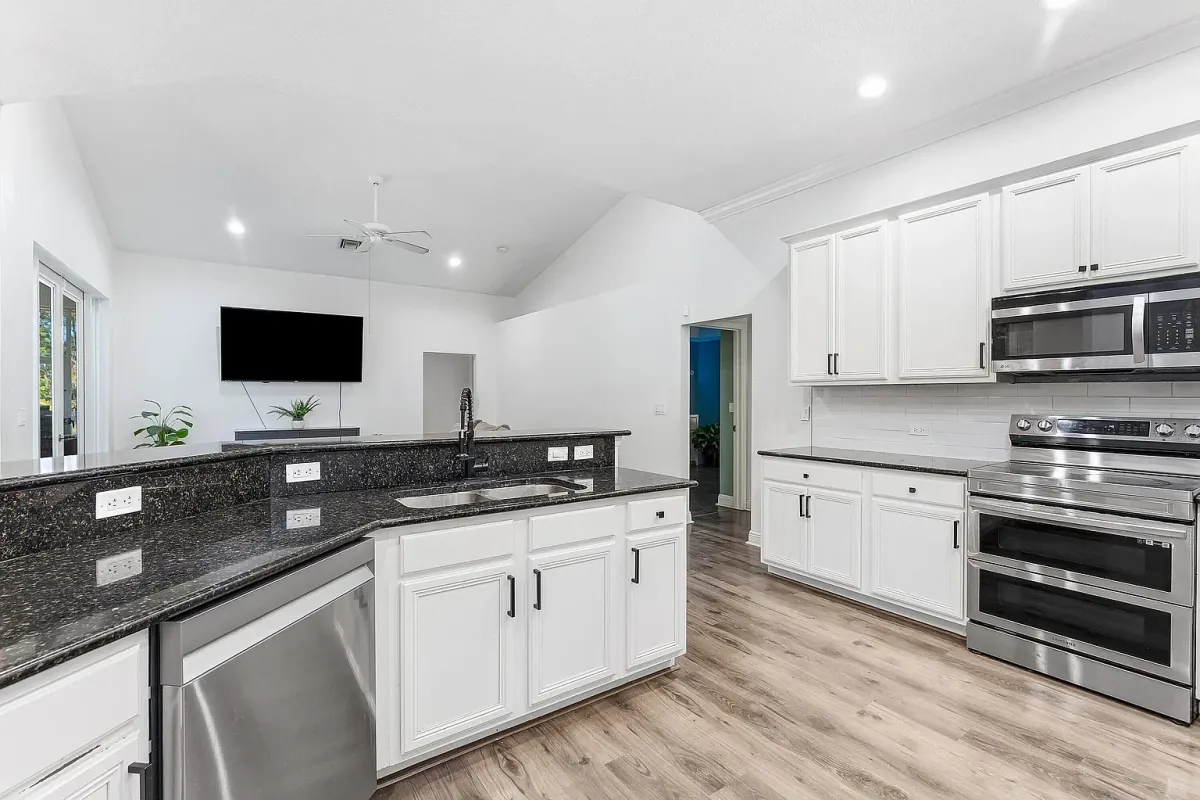 Kitchen with white cabinetry, dark granite counters and stainless steel appliances