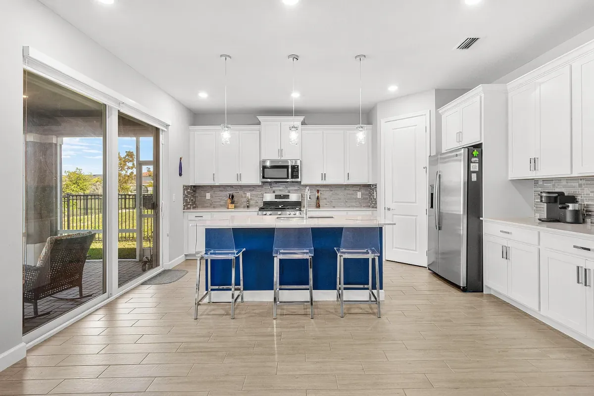 Kitchen with white cabinetry, center island with seating, stainless appliances and sliding doors to the patio