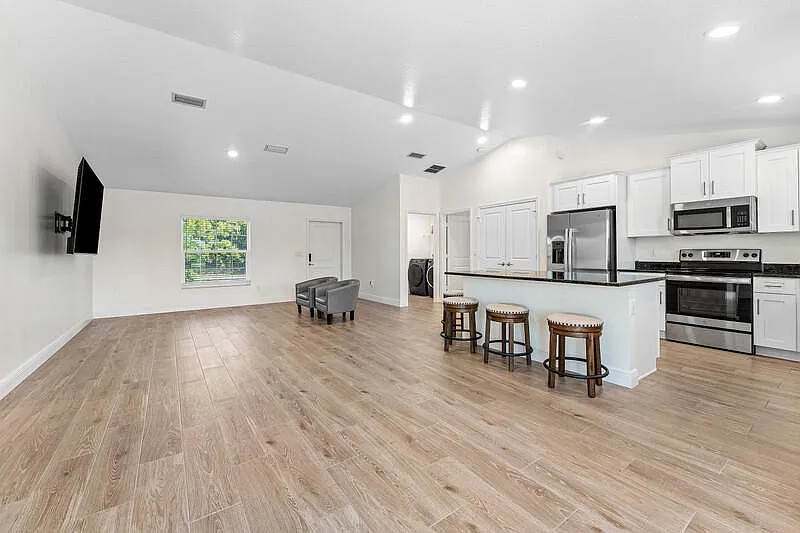 Open kitchen with white cabinetry, center island and breakfast bar seating