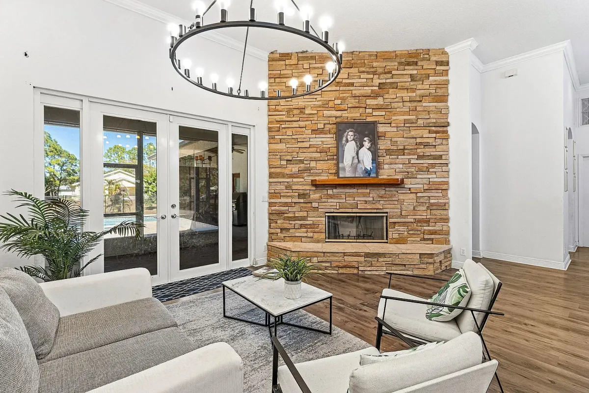 Living room with floor-to-ceiling stone fireplace, chandelier and French doors to the lanai