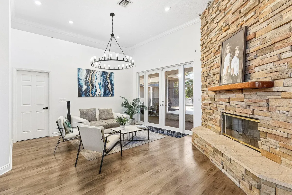 Wider view of the living room, showing the stone fireplace wall and French doors