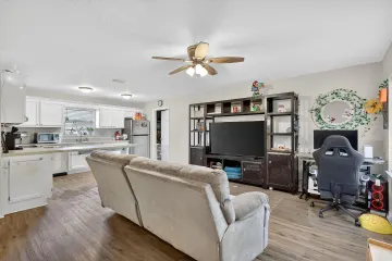 Open living room looking through to the kitchen, with white cabinets and laminate flooring
