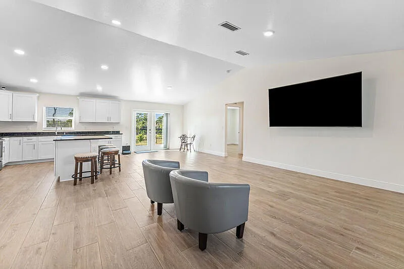 Living room with wall-mounted TV and open sightline to the kitchen