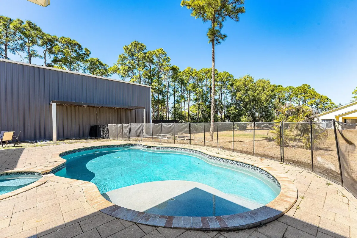 Pool and spa seen from the yard, with the steel building directly behind