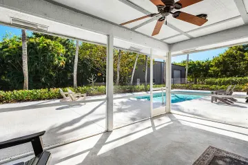 Screened patio with a ceiling fan looking out to the pool and the metal workshop