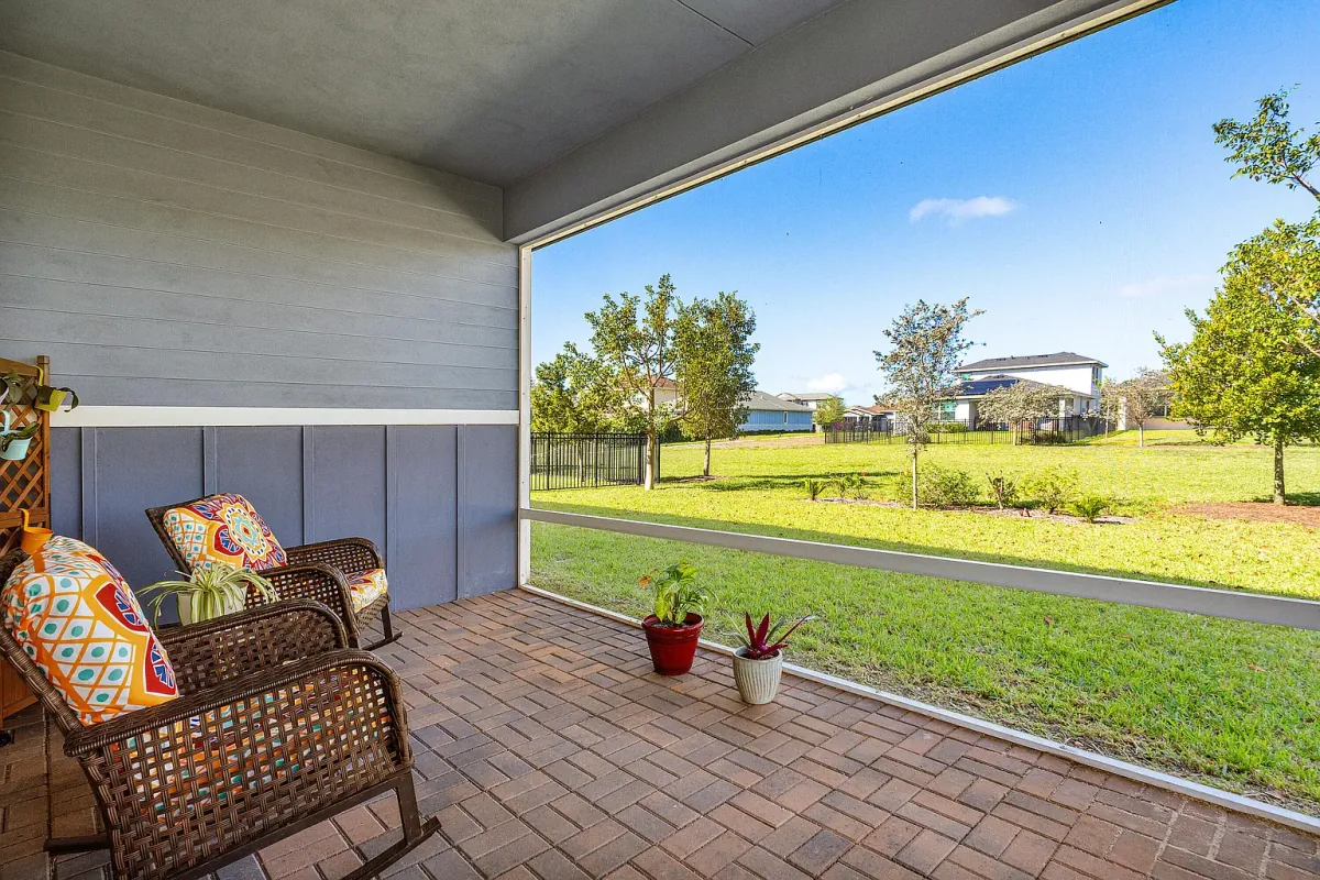 Screened-in rear porch with paver flooring, looking out over the lawn