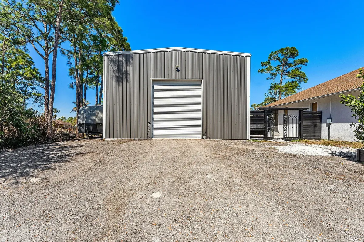 2023 red iron steel building with a 14-foot roll-down door and gravel approach